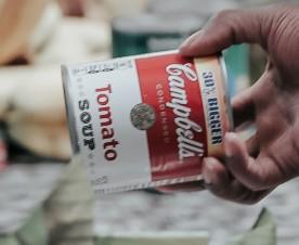man handing can in charitable act