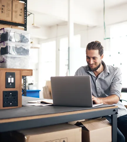 Man in his 30s smiling and working on his computer