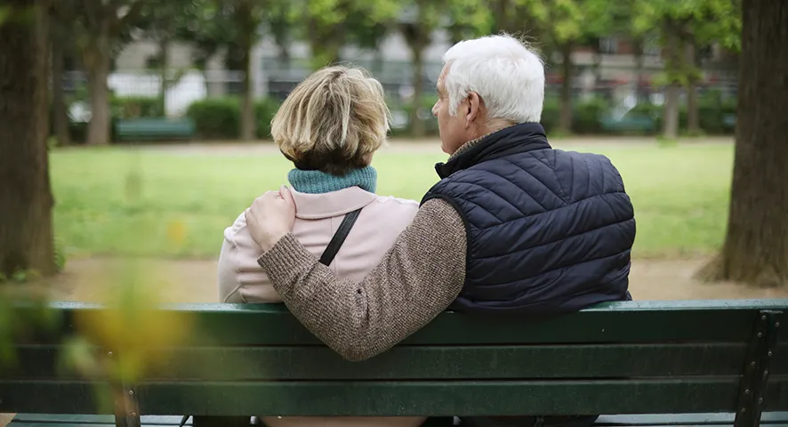 Elderly couple sitting on a park bench together