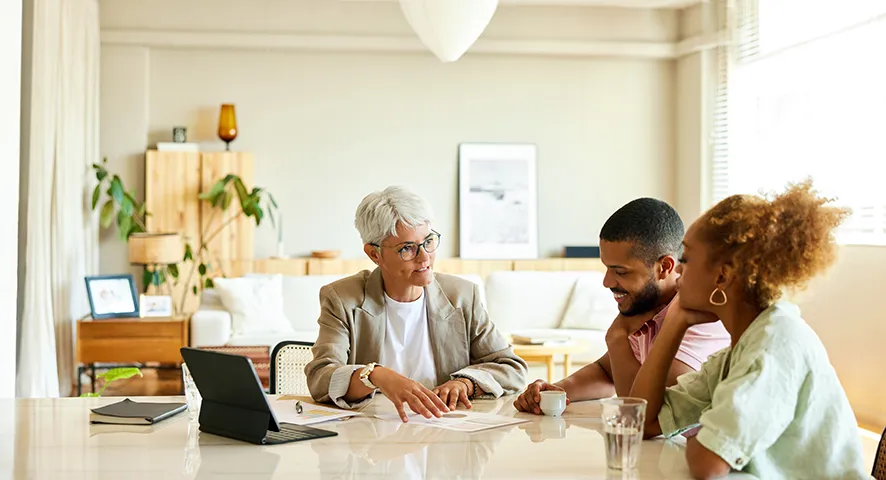 Experienced female advisor speaking with her two clients at the table