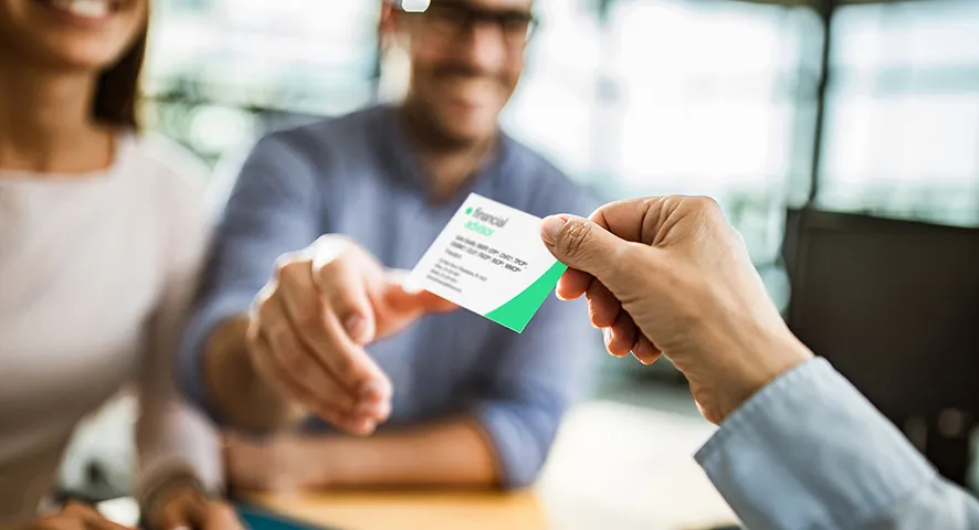 Female advisor handing a married couple her business card