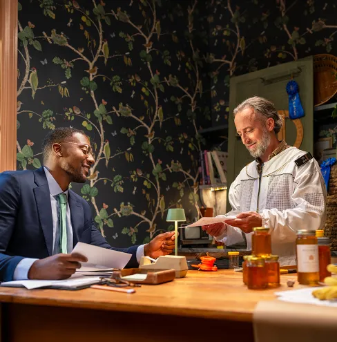 Man in beekeeper suit meeting with a financial advisor